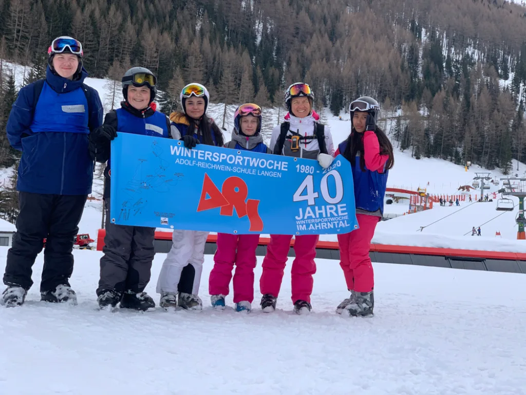 Jugendliche mit Skibrillen halten das Banner „40 Jahre“ in die Kamera.